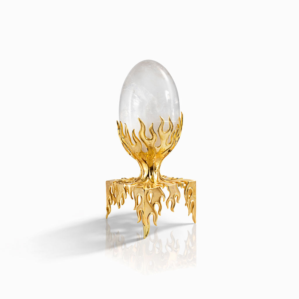 Decorative object with a clear egg-like structure on a gold stand against a white background