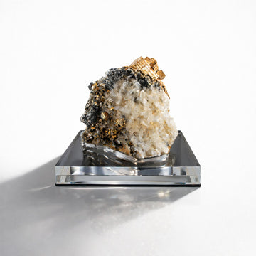 Mineral specimen pyrite, rock crystal and calcite on a clear acrylic stand against a white background