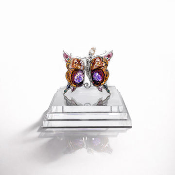 Butterfly-shaped jewelry with gemstones on a reflective surface