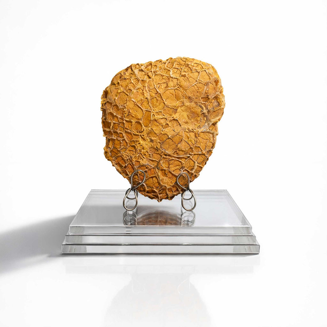 Decorative object resembling a textured sphere on a clear stand against a white background