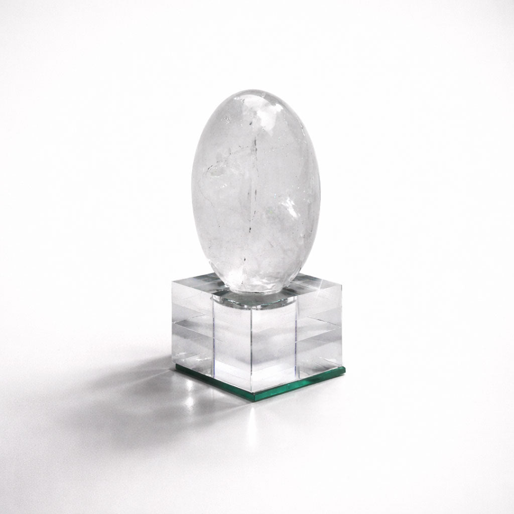 Clear crystal egg on a square pedestal against a white background