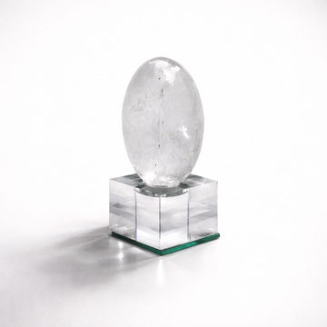 Clear crystal egg on a square pedestal against a white background